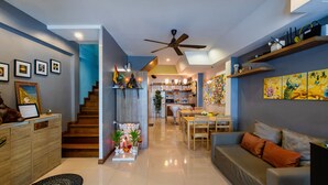 A modern living room with a sofa, a dining table, and a staircase leading to the kitchen. - Restiny Hostel (Bangkok)