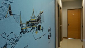 A hallway with a wall mural of a building and a door. - Restiny Hostel (Bangkok)