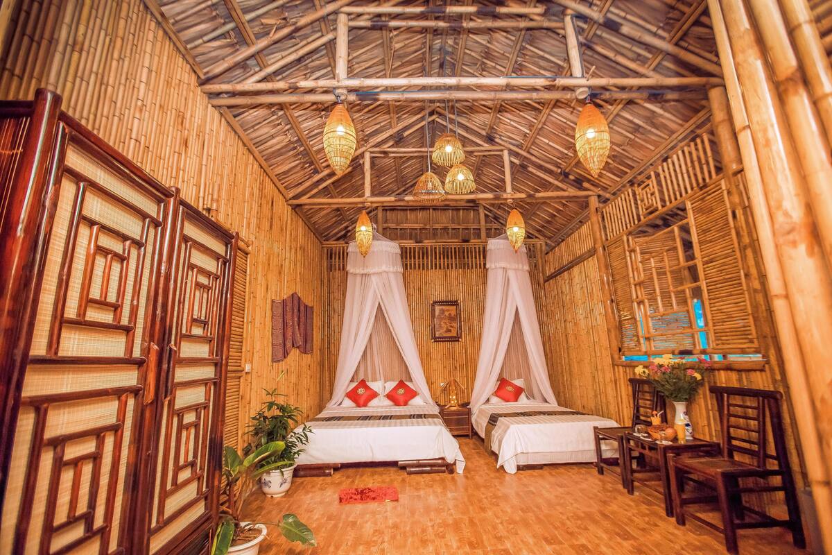 A room with two beds, bamboo walls, and a thatched roof.