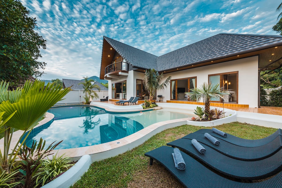 A modern house with a swimming pool, outdoor seating, and a balcony.