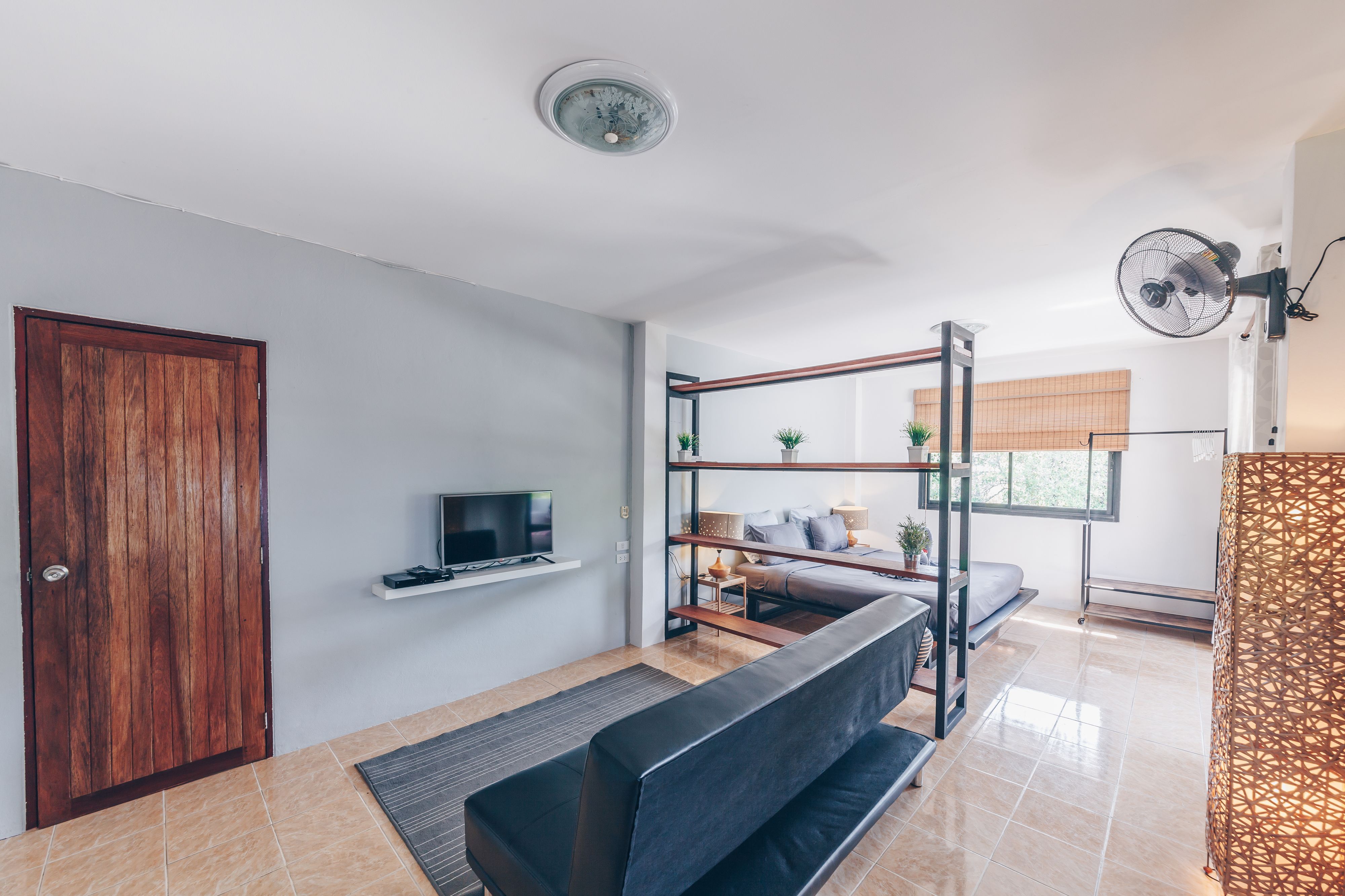 A modern living room with a sofa, TV, and a wooden door.