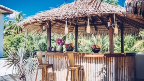A bamboo bar with two chairs, a thatched roof, and a view of tropical vegetation. - Coco Lilly Villas (Ko Pha-ngan)