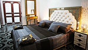 A bedroom with a large bed, a dresser, a mirror, and a door.