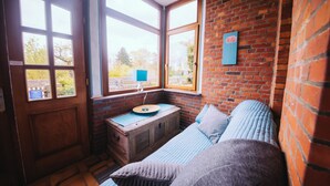 Una habitación acogedora con un banco de madera, una cama con ropa de cama azul y una pared de ladrillo.