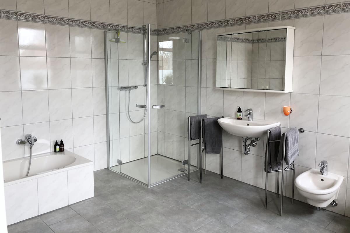 A modern bathroom with a glass-enclosed shower, a freestanding bathtub, a sink, and a bidet.