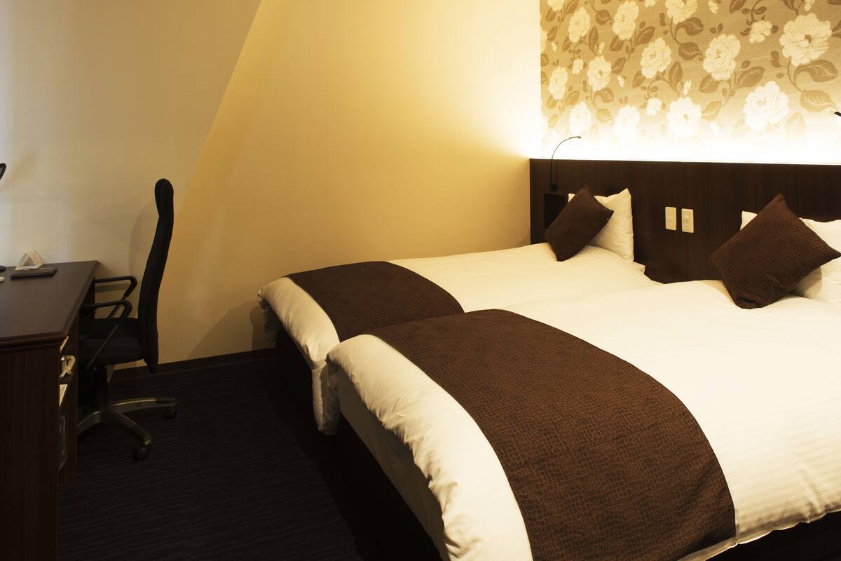 A hotel room with a large bed, a desk, and a chair.