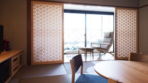 A traditional Japanese room with tatami flooring, a low table, and a sliding door leading to a balcony with a view of snow-covered mountains. - Kushiro Century Castle Hotel (Kushiro)