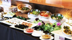 A buffet with various dishes and drinks, including salads, meats, and desserts, arranged on a counter with a wooden backdrop. - Kushiro Century Castle Hotel (Kushiro)