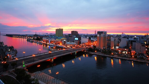 A cityscape at dusk with a river, bridges, and buildings. - Kushiro Century Castle Hotel (Kushiro)