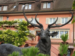 A deer statue in front of a building with multiple windows and a balcony. - Landhotel Hirschen (Truellikon)