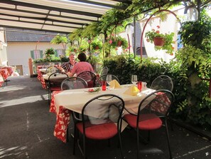 An outdoor dining area with tables and chairs, covered by a pergola with climbing plants. - Landhotel Hirschen (Truellikon)