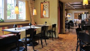 Un restaurante con vigas de madera, mesas, sillas y lámparas colgantes.