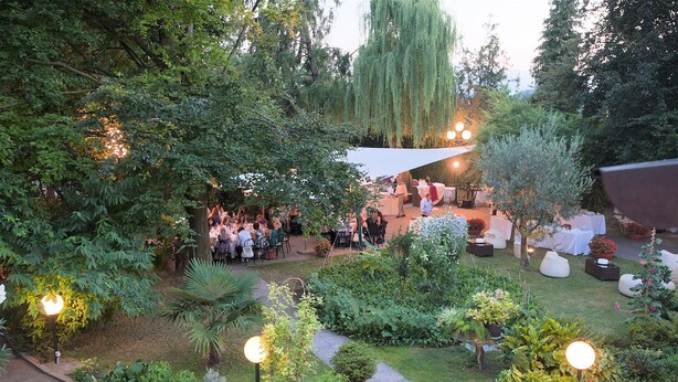 An outdoor garden with tables and chairs, surrounded by various plants and trees. - Hotel Piroga Padova (Selvazzano Dentro)