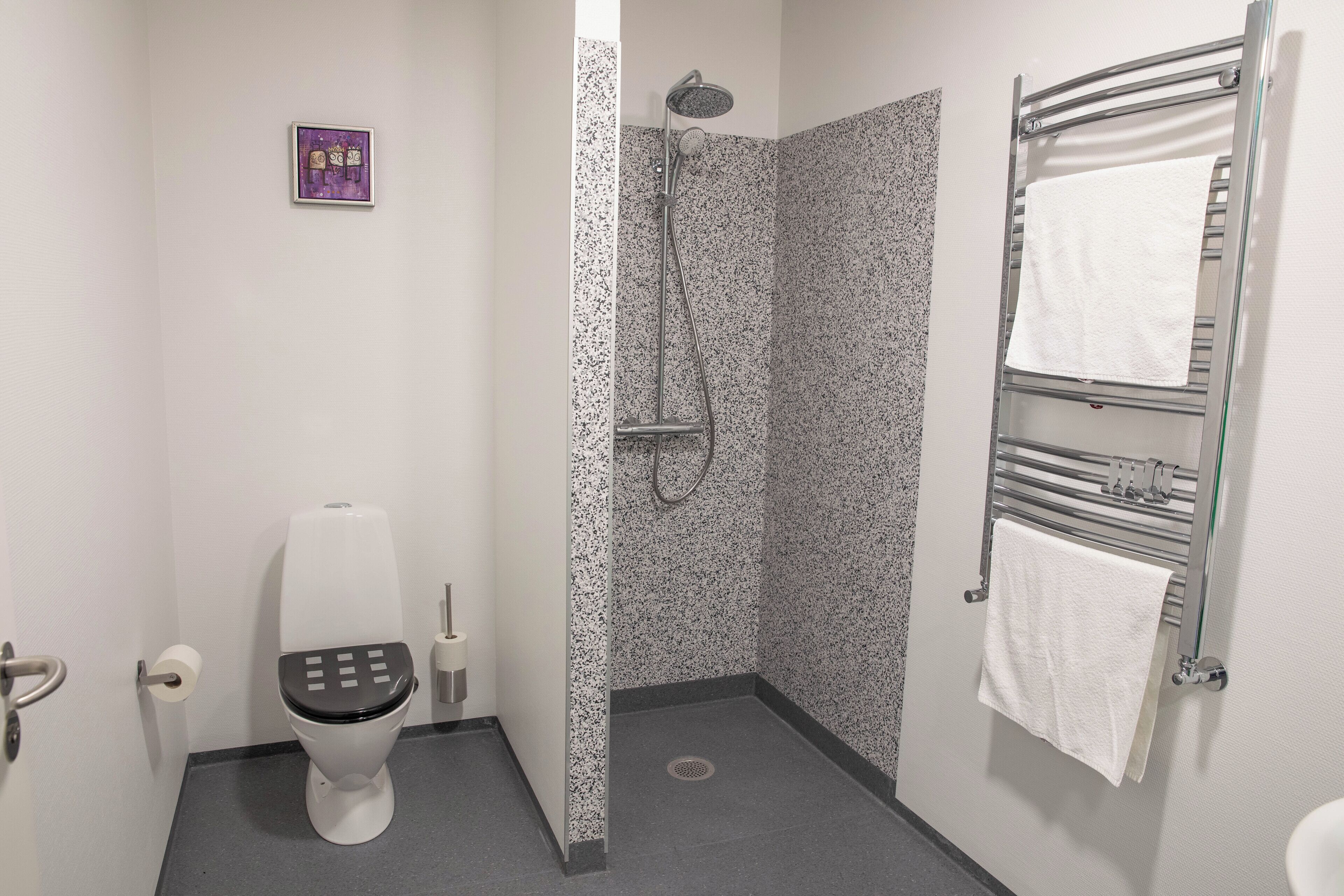 A modern bathroom with a toilet, shower, and towel rack.