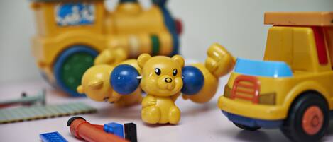 A toy train, a toy truck, and a toy bear on a table.