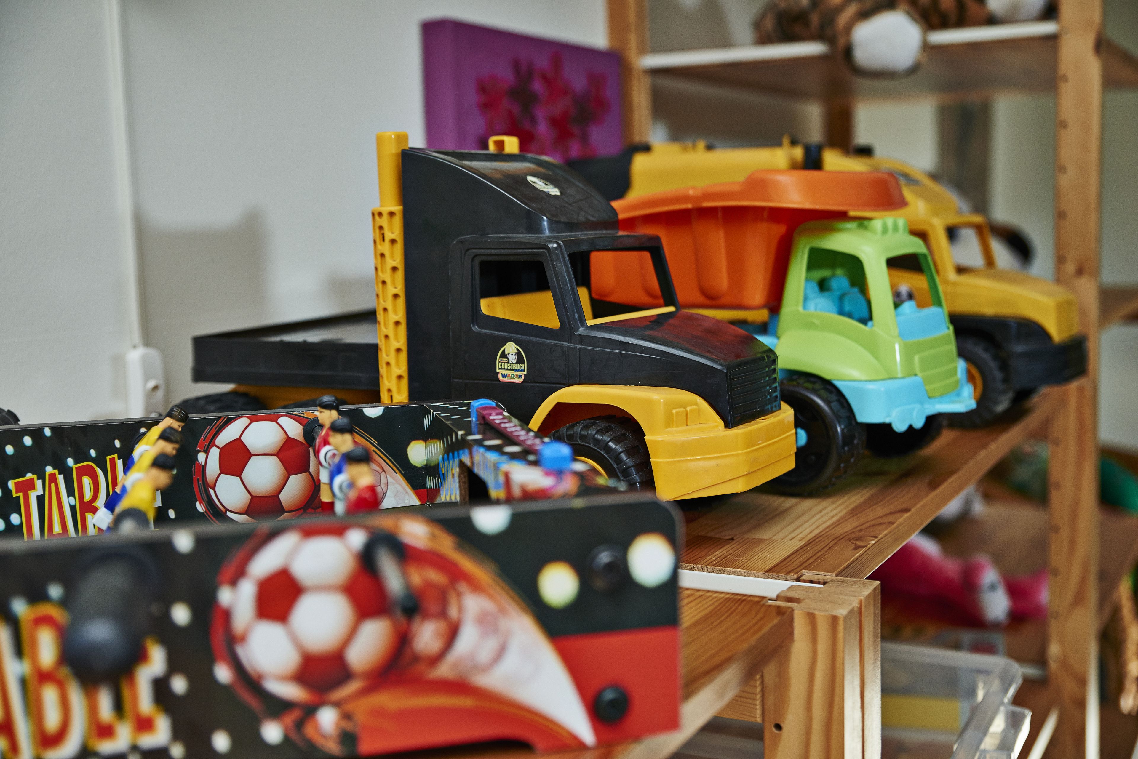 A variety of toy vehicles and sports balls on a shelf.