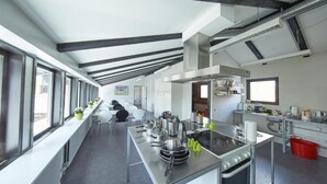 Una cocina moderna con electrodomésticos de acero inoxidable, una encimera larga y vistas amplias a través de grandes ventanales.