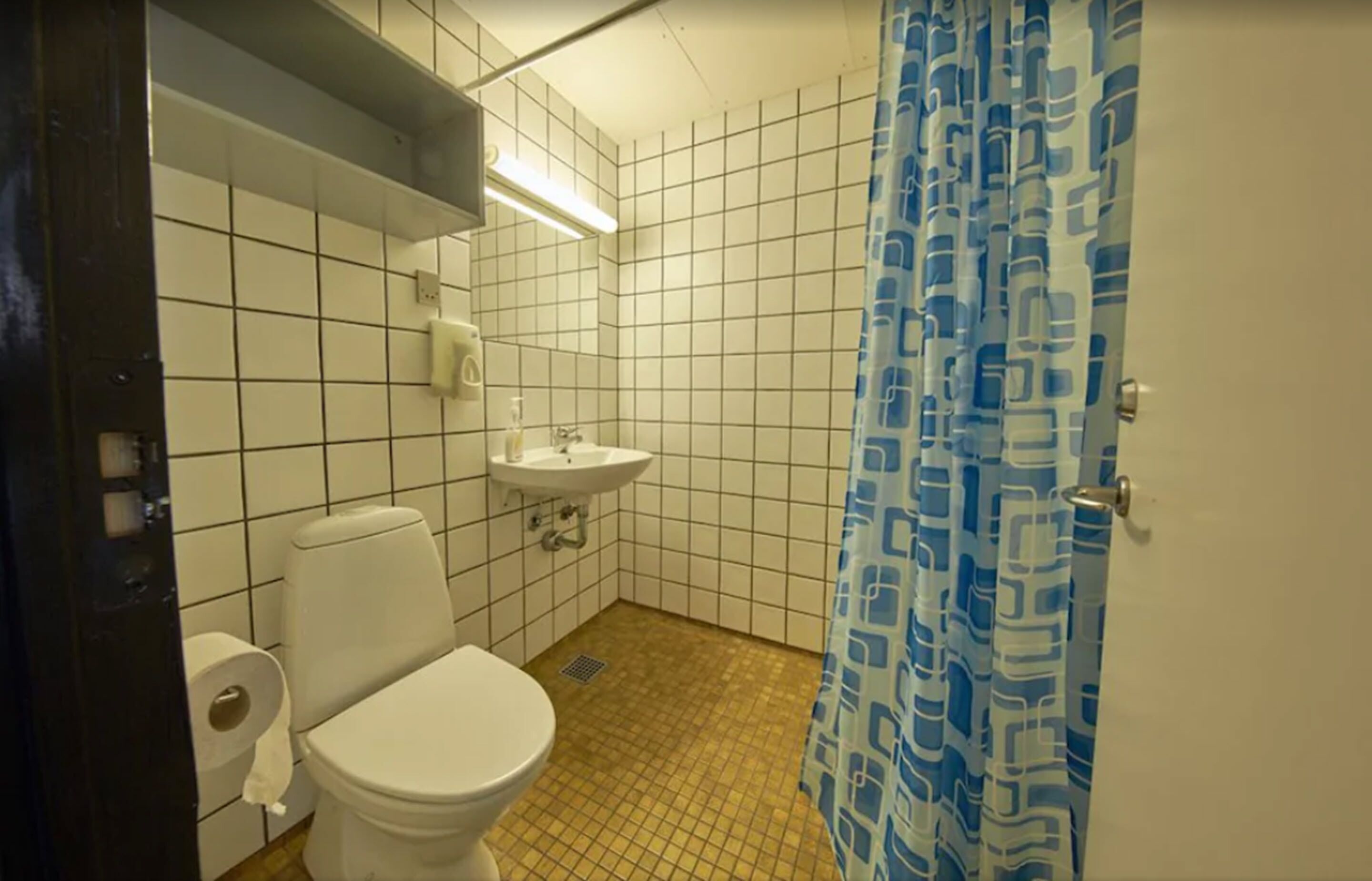 A small bathroom with a toilet, sink, and tiled walls.