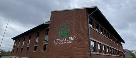 Un edificio con un letrero que dice "STAY AND SLEEP" y "DESCANSA - RELÁJATE - RECARGA".