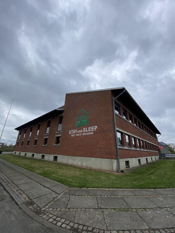 A building with a sign reading "STAY AND SLEEP" and "REST - RELAX - RECHARGE". - Stay and Sleep (Grindsted)