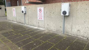 A parking area with electric vehicle charging stations and signs indicating parking restrictions.
