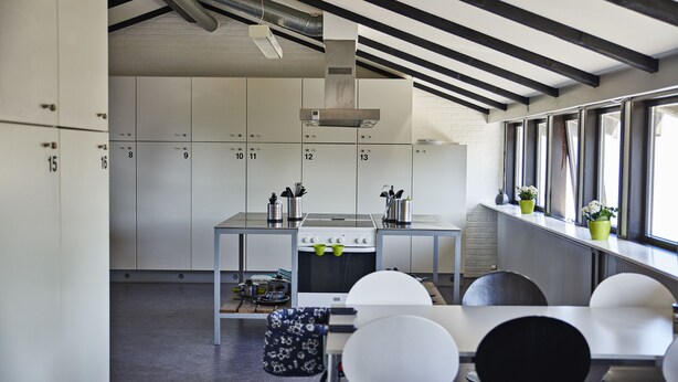 Una cocina moderna con armarios blancos, una estufa y un comedor con sillas blancas.
