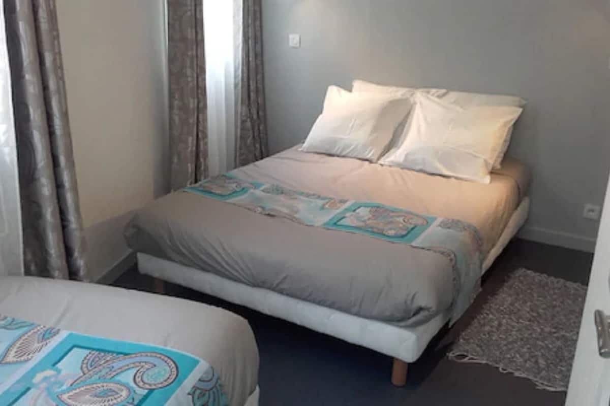 Quarto pequeno e bem arrumado com uma cama de solteiro e um sofá-cama ou cama extra.