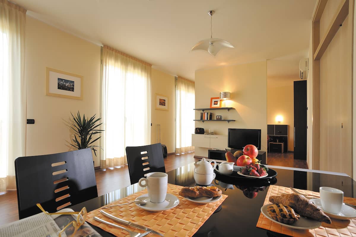 A dining area with a table set for two, including plates of food, cups, and cutlery.