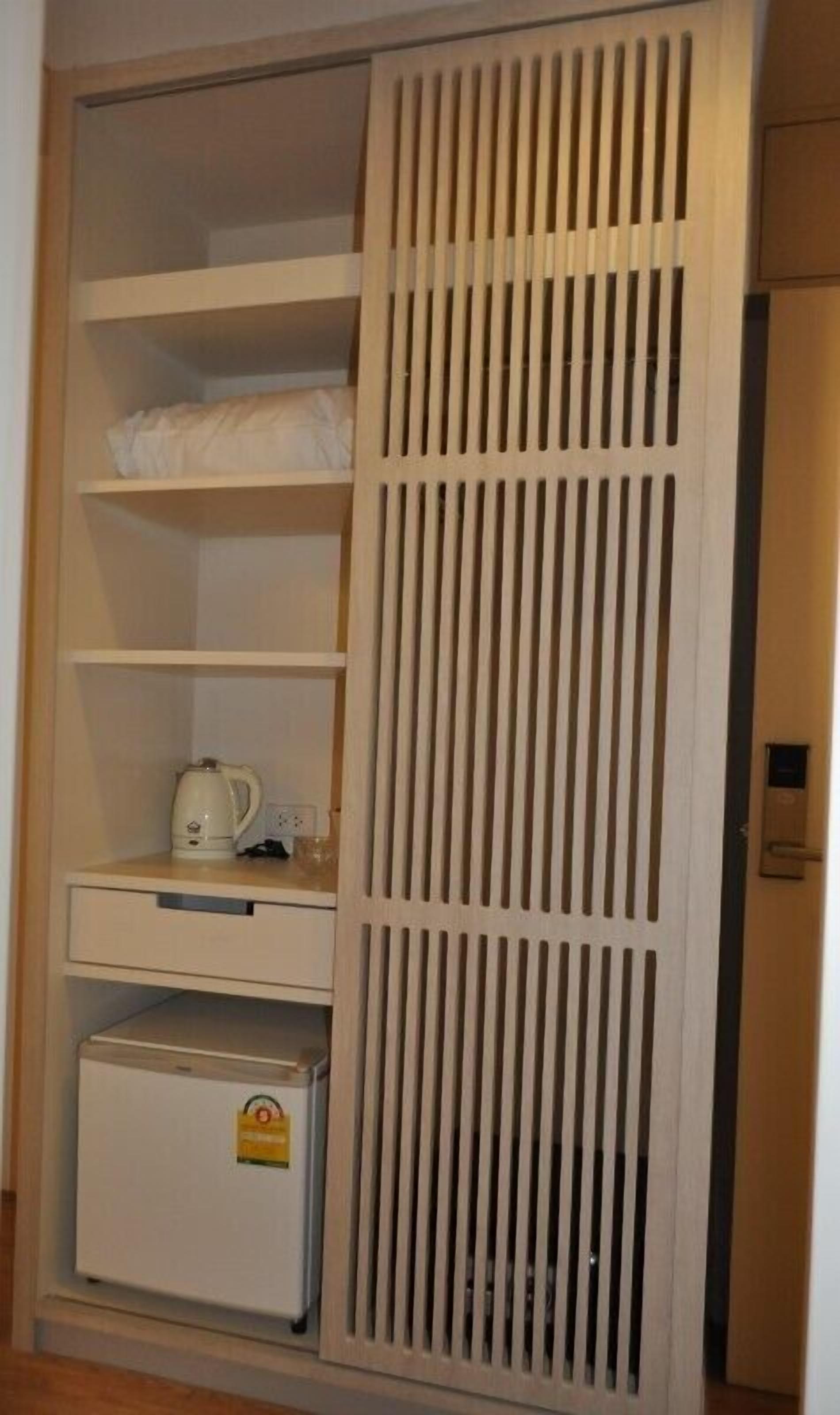 A wardrobe with multiple shelves and a small refrigerator.