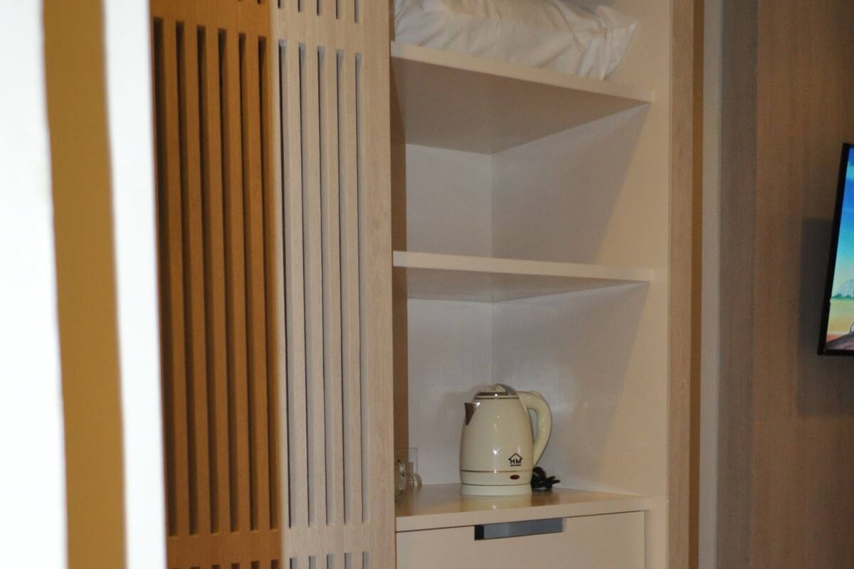Un mueble compacto con refrigerador, hervidor y un estante pequeño.