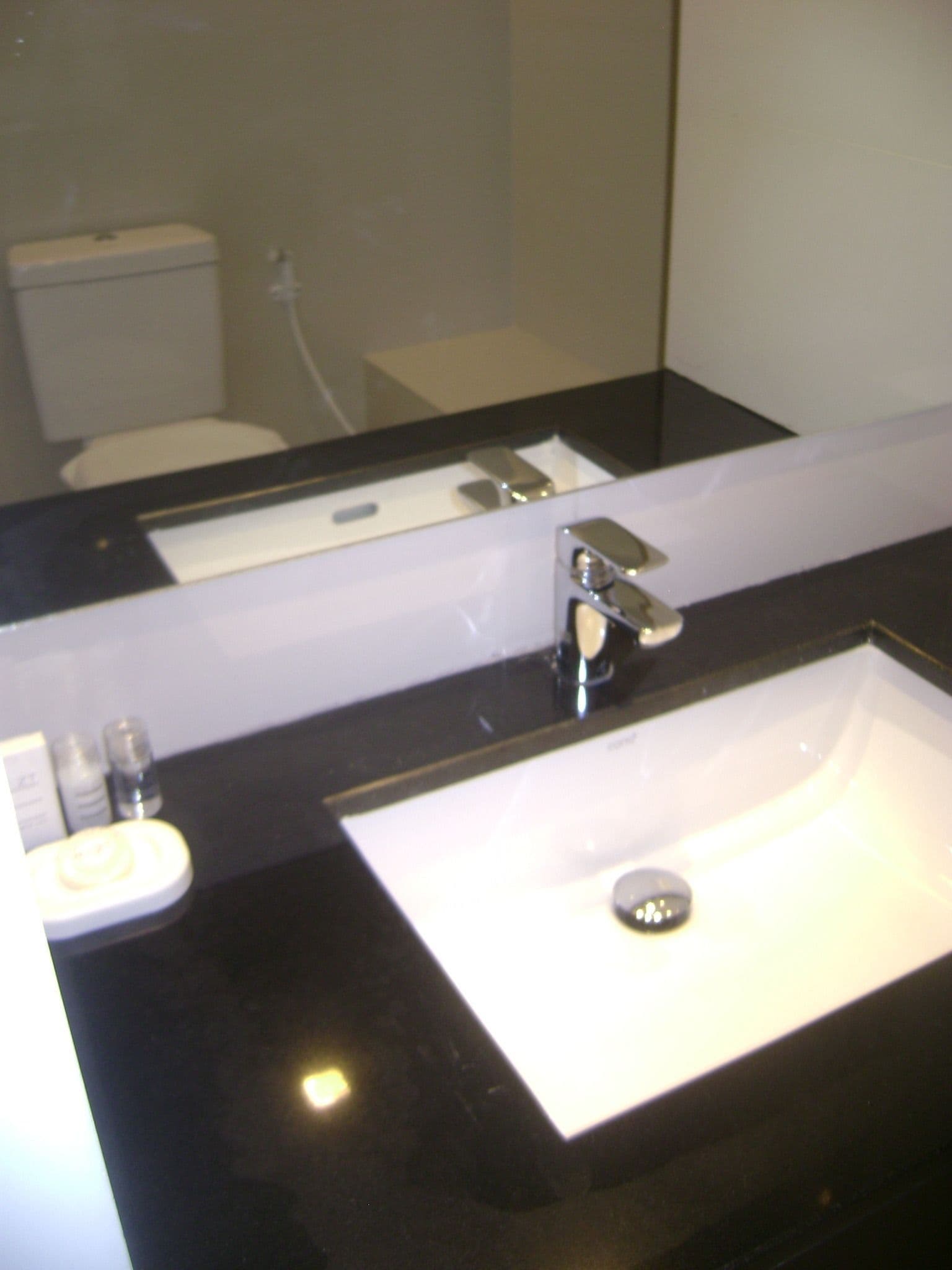 Un bagno con un piano d'appoggio nero, un lavandino bianco e uno specchio.
