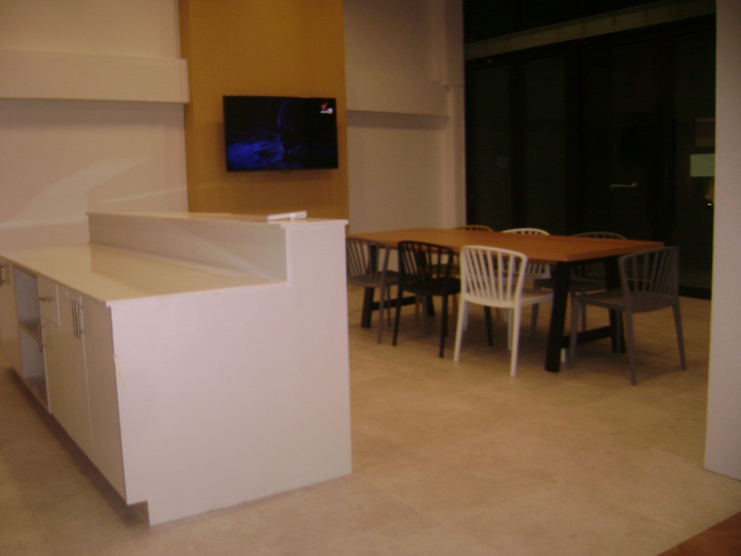 A modern dining area with a white counter and wooden chairs.