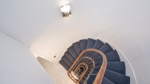 A spiral staircase with a wooden handrail and a light fixture above. - Hotel Esperance (Paris)
