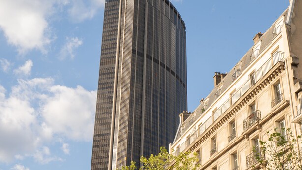A tall modern skyscraper with a curved facade and a classical building with balconies in the foreground. - Hotel Esperance (Paris)