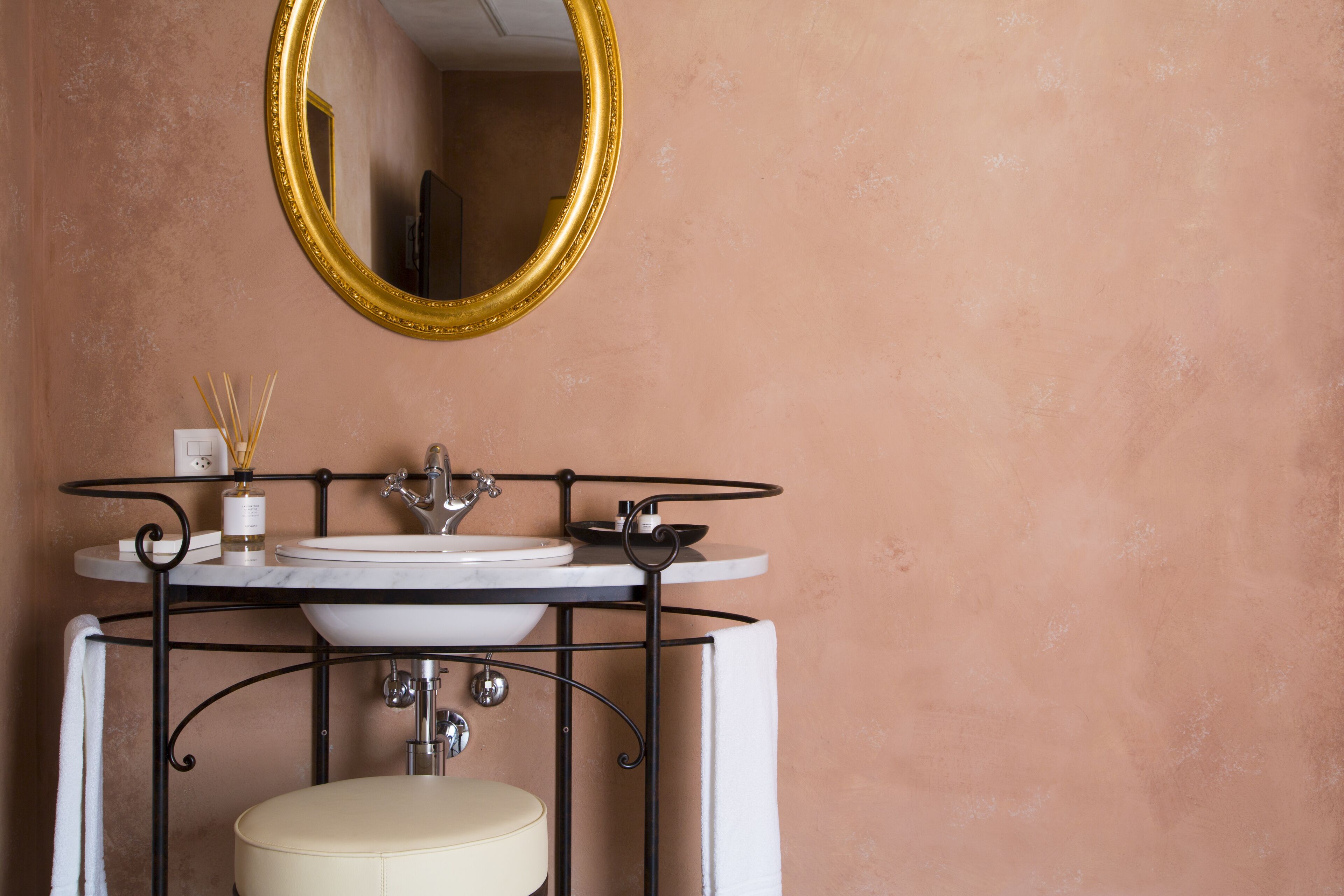 Une salle de bain avec un miroir rond, un lavabo et des toilettes.