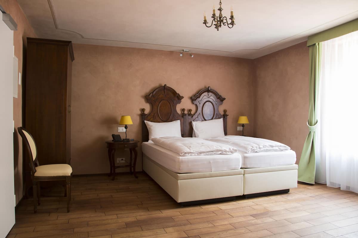 Ein Schlafzimmer mit einem Doppelbett, zwei Nachttischen inklusive Lampen, einem Holzstuhl und einer Pendelleuchte.