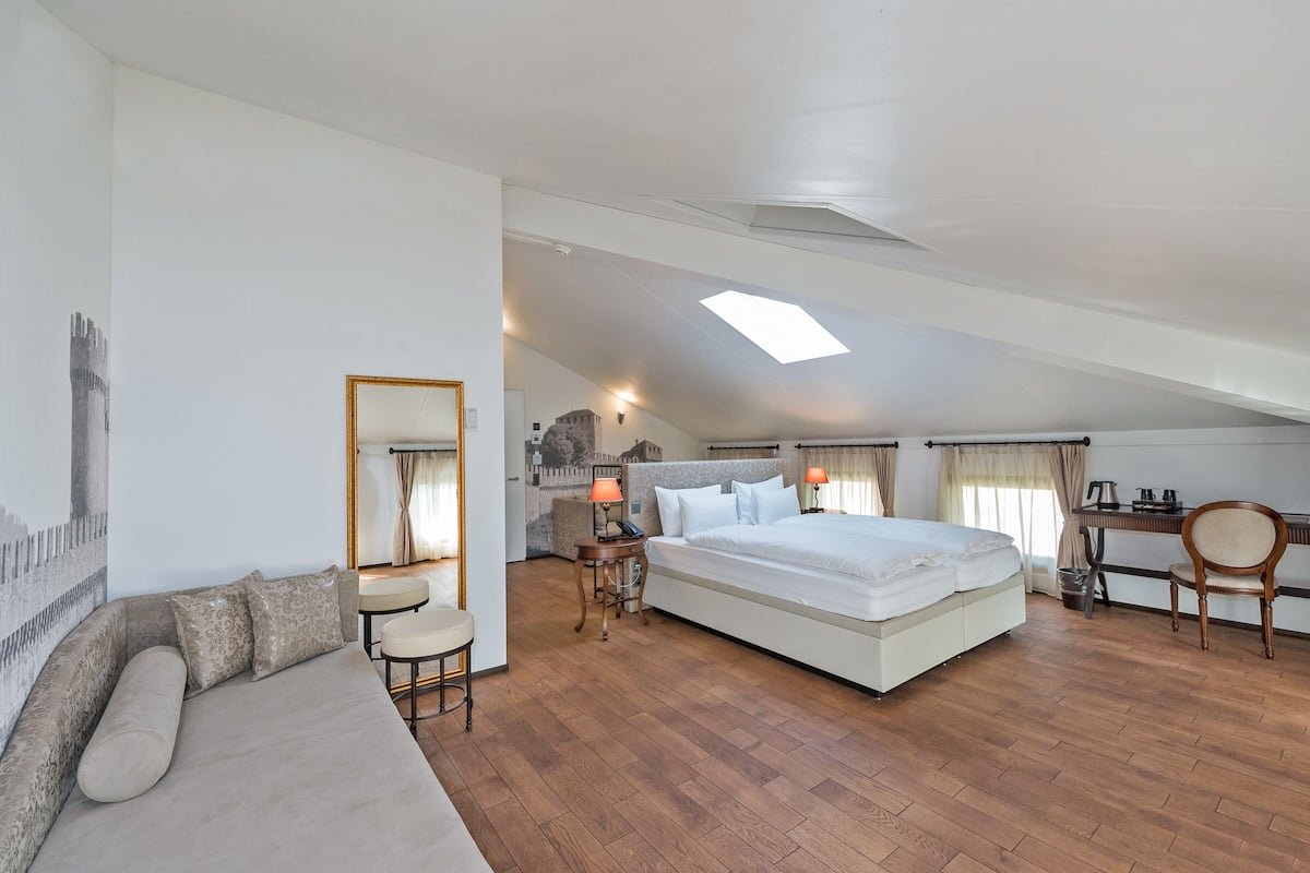 Ein geräumiges Schlafzimmer mit einem großen Bett, einer Sitzecke, einem Schreibtisch und einem Dachfenster.