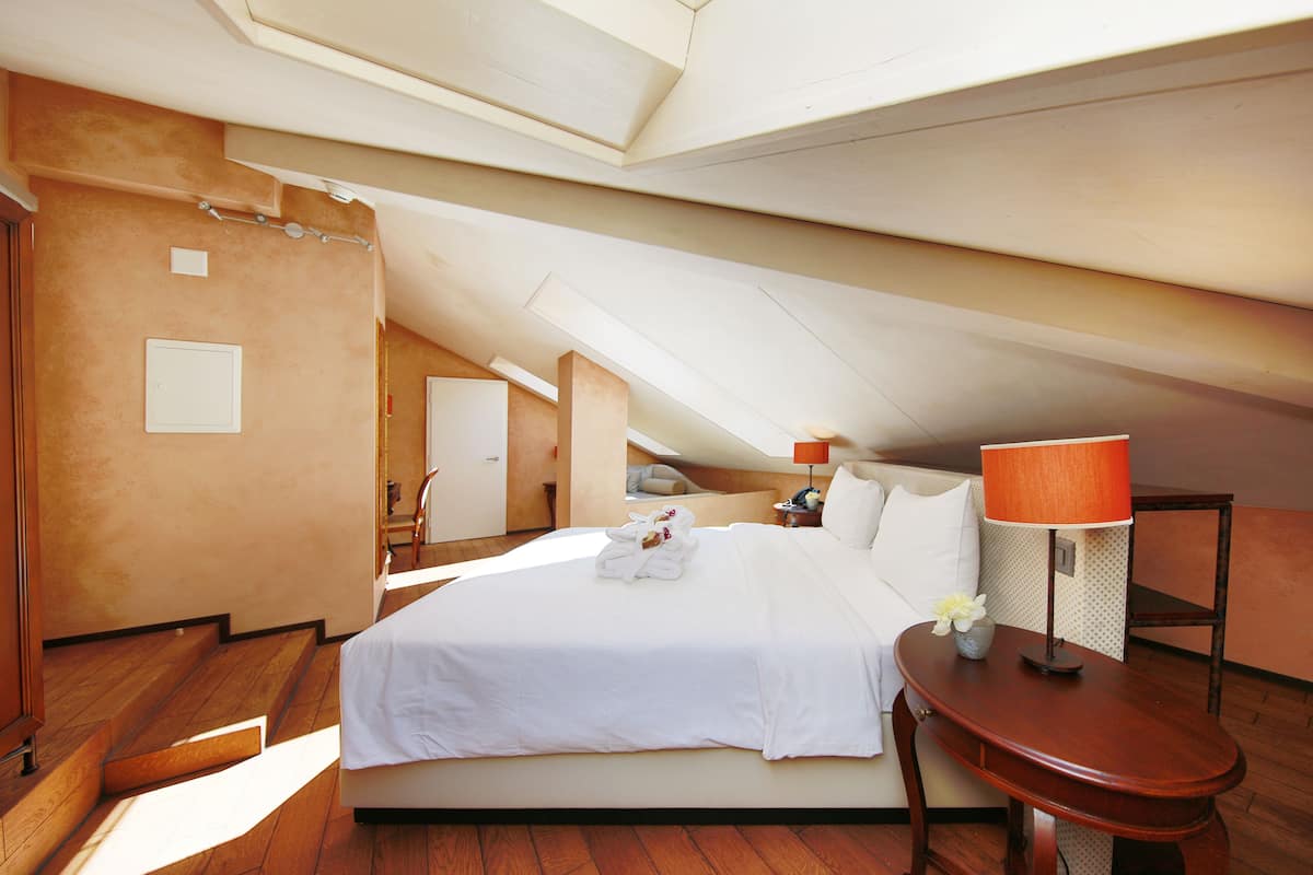 Ein geräumiges Zimmer mit einem großen Bett, Holzboden und einem Oberlicht.