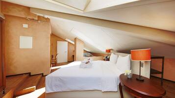 Una habitación amplia con una cama grande, piso de madera y tragaluz.