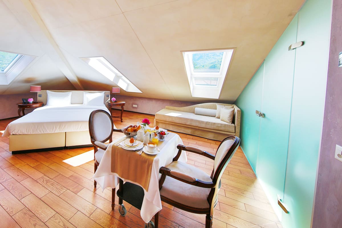Ein Schlafzimmer mit einem großen Bett, einem Esstisch mit Frühstück und zwei Oberlichtern.