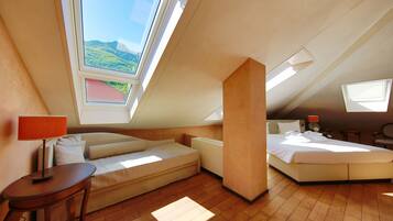 Une chambre confortable située sous les toits, avec une grande fenêtre de toit, un canapé, un lit et une petite table.