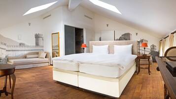 A bedroom with a large bed, a desk, a chair, and a sofa. There are two lamps on the desk and a window with curtains.