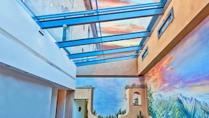 Un intérieur moderne agrémenté d’une verrière, d’une fresque représentant un paysage de montagne et d’un clocher.