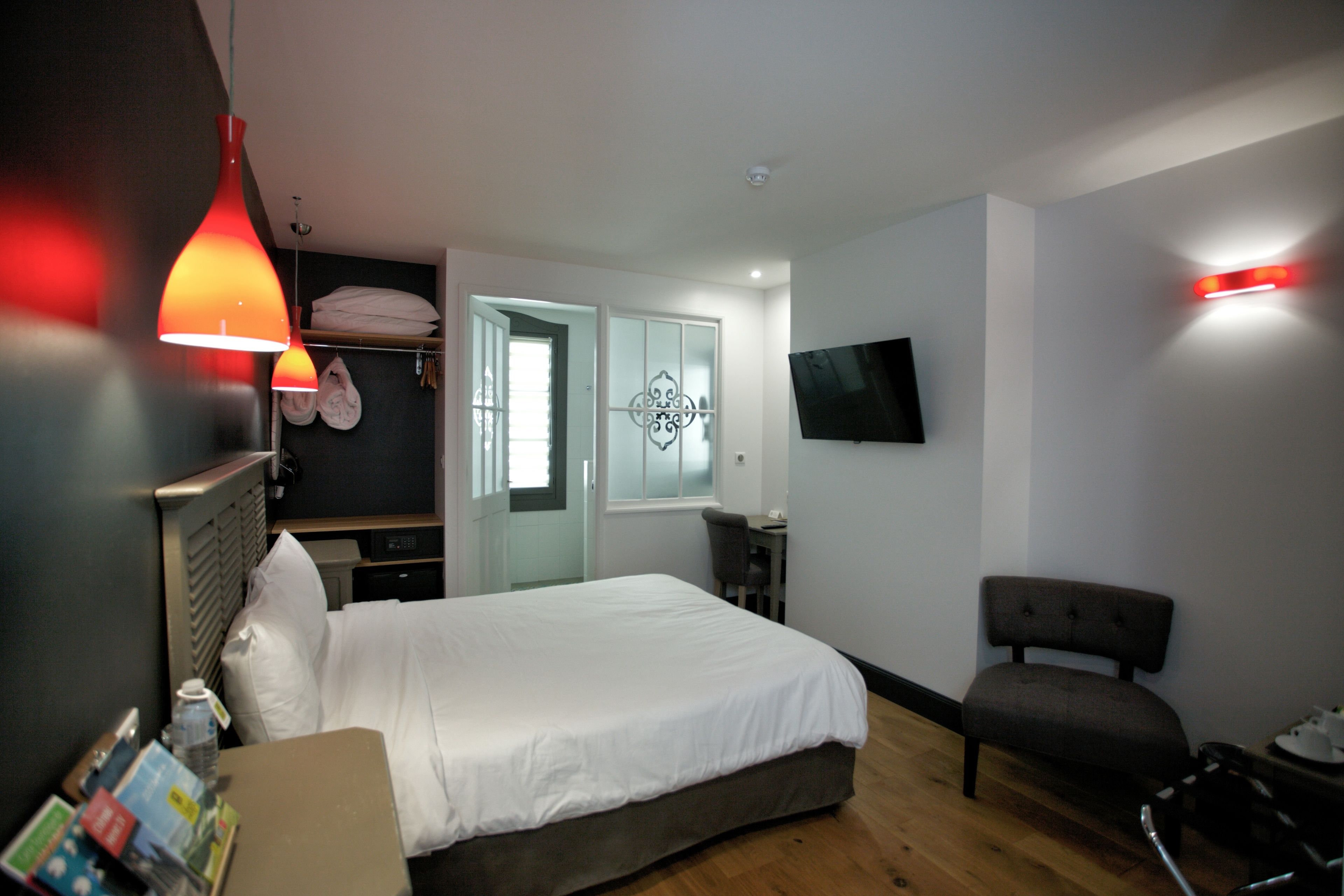 A hotel room with a bed, a desk, a chair, a TV, and a wardrobe.