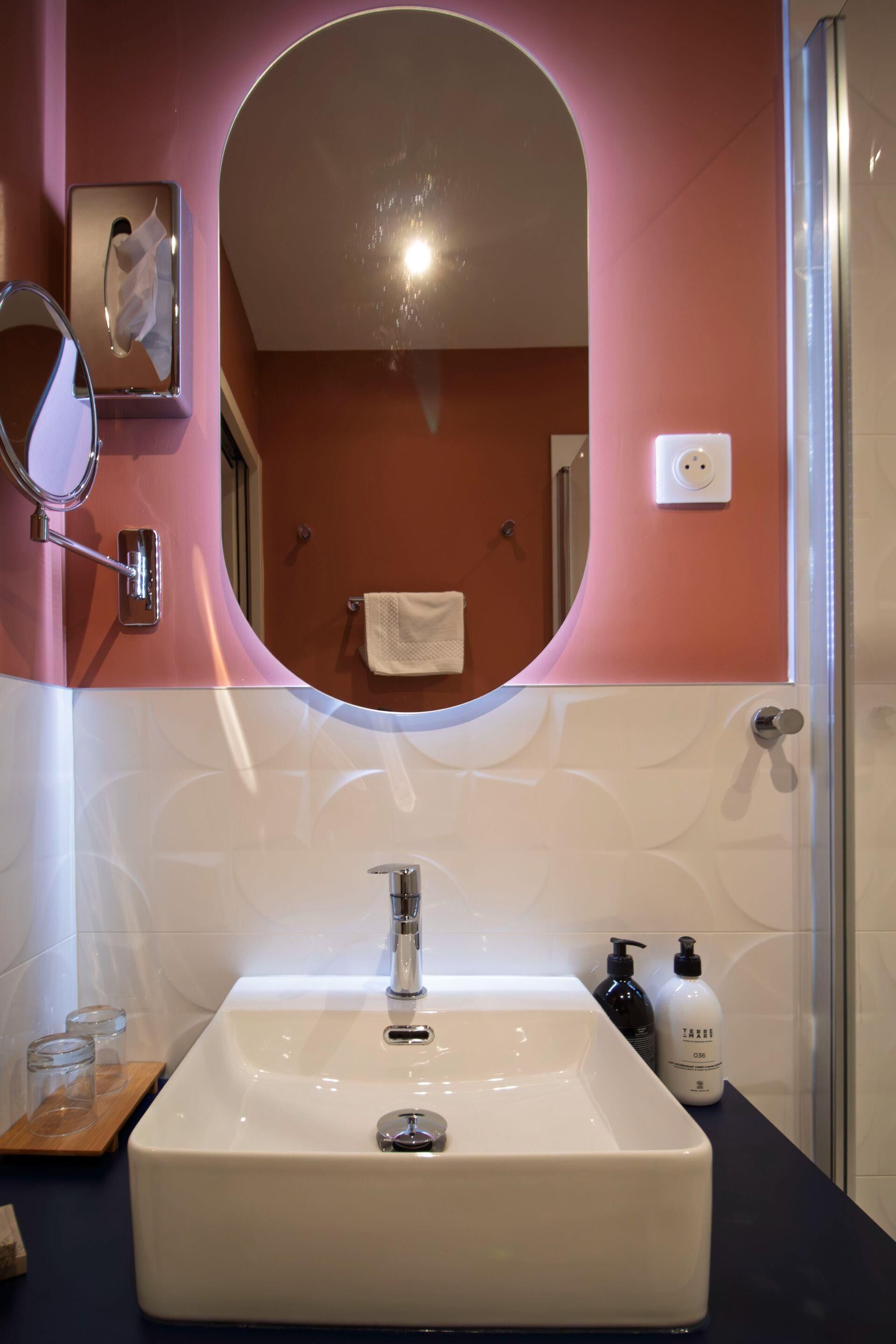 A bathroom with a white sink, a mirror, and two bottles of toiletries.