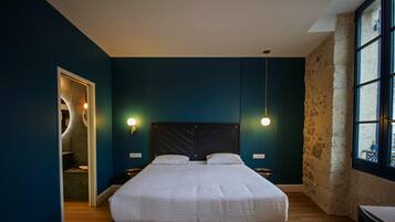 A bedroom with a bed, two bedside tables, a window, and a door.