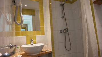 Een badkamer met een wit wastafel, geel betegelde wanden en een douche met gordijn.