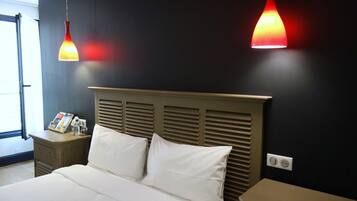 Una habitación de hotel con una cama, mesitas de noche, una revista y dos lámparas colgantes.