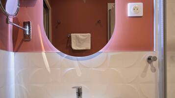 Ein Badezimmer mit einem weißen Waschbecken, einem Spiegel und zwei Shampoo-Flaschen.
