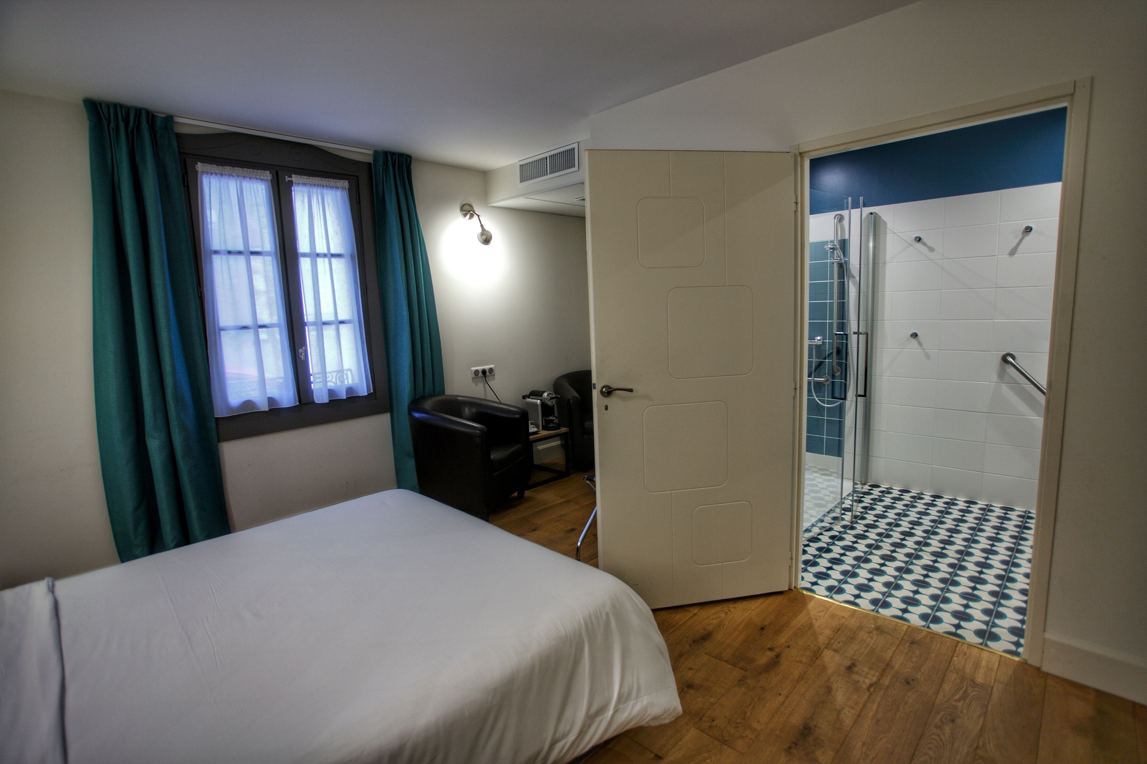 Un dormitorio con cama, escritorio y ba ño con ducha y suelo de baldosas.